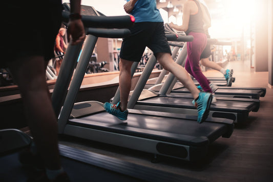 A group of individuals engaged in interval training on treadmills in a modern gym setting.